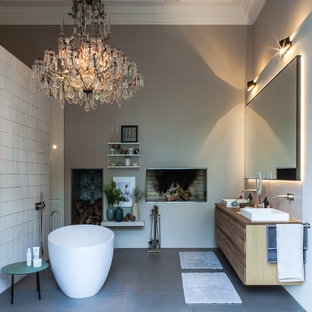 Großes Modernes Badezimmer En Suite mit flächenbündigen Schrankfronten, hellen Holzschränken, freistehender Badewanne, bodengleicher Dusche, Wandtoilette, weißen Fliesen, Kalkfliesen, beiger Wandfarbe, Keramikboden, Einbauwaschbecken, Mineralwerkstoff-Waschtisch, grauem Boden, offener Dusche und brauner Waschtischplatte in Hamburg
