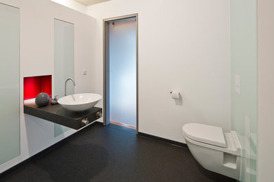 Mittelgroßes Modernes Badezimmer mit Wandtoilette mit Spülkasten, weißer Wandfarbe, Aufsatzwaschbecken, Granit-Waschbecken/Waschtisch, schwarzem Boden und schwarzer Waschtischplatte in Hamburg