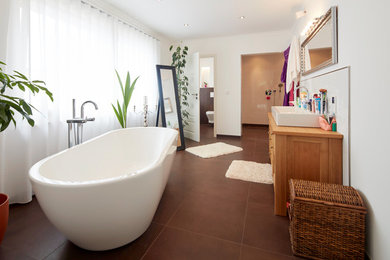 Medium sized contemporary ensuite bathroom in Bremen with flat-panel cabinets, medium wood cabinets, a freestanding bath, a wall mounted toilet, white walls, a vessel sink, wooden worktops, brown floors and brown worktops.