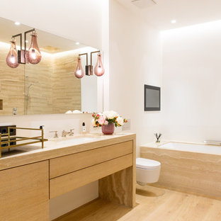 Mittelgroßes Modernes Badezimmer En Suite mit flächenbündigen Schrankfronten, hellen Holzschränken, Einbaubadewanne, Wandtoilette, weißer Wandfarbe, hellem Holzboden, beigem Boden, beiger Waschtischplatte, Unterbauwaschbecken und Waschtisch aus Holz in München