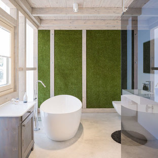 Großes Modernes Badezimmer En Suite mit bodengleicher Dusche, Wandtoilette, grüner Wandfarbe, Betonboden, Wandwaschbecken, offener Dusche, profilierten Schrankfronten, hellen Holzschränken, freistehender Badewanne und grauem Boden in Sonstige