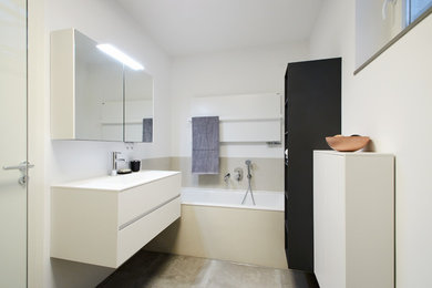ベルリンにあるお手頃価格の中くらいなコンテンポラリースタイルのおしゃれなバスルーム (浴槽なし) (フラットパネル扉のキャビネット、白いキャビネット、ドロップイン型浴槽、オープン型シャワー、壁掛け式トイレ、白い壁、一体型シンク、人工大理石カウンター、グレーの床、オープンシャワー、白い洗面カウンター) の写真