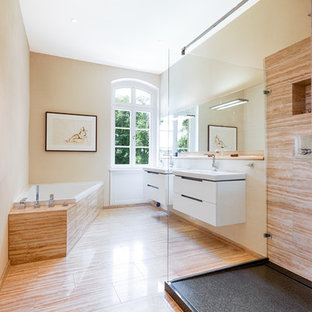 Großes Klassisches Duschbad mit Eckbadewanne, bodengleicher Dusche, braunen Fliesen, Travertinfliesen, beiger Wandfarbe, Travertin, integriertem Waschbecken, Mineralwerkstoff-Waschtisch, beigem Boden, offener Dusche, flächenbündigen Schrankfronten und weißen Schränken in Hannover