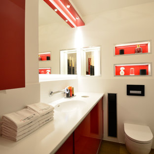 Mittelgroßes Modernes Duschbad mit flächenbündigen Schrankfronten, roten Schränken, Wandtoilette, weißen Fliesen, Porzellanfliesen, weißer Wandfarbe, integriertem Waschbecken und weißer Waschtischplatte in Hannover