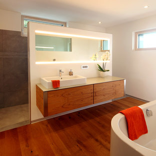 Mittelgroßes Modernes Badezimmer En Suite mit flächenbündigen Schrankfronten, hellbraunen Holzschränken, freistehender Badewanne, braunen Fliesen, weißer Wandfarbe, braunem Holzboden, Aufsatzwaschbecken, braunem Boden und beiger Waschtischplatte in München