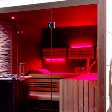 Einbausauna fürs Bad mit großzügiger Glasfront und Naturstein hinter dem Saunaof