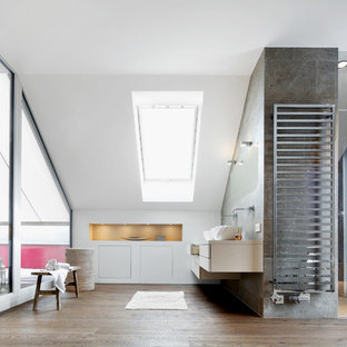 Modernes Badezimmer mit flächenbündigen Schrankfronten, weißen Schränken, Duschnische, grauen Fliesen, weißer Wandfarbe, braunem Holzboden, Aufsatzwaschbecken, braunem Boden, Falttür-Duschabtrennung und weißer Waschtischplatte in München