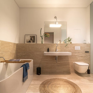 Mittelgroßes Modernes Duschbad mit freistehender Badewanne, Wandtoilette, beigefarbenen Fliesen, Steinplatten, Kalkstein, Wandwaschbecken, beigem Boden und weißer Wandfarbe in Berlin