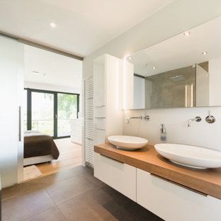 Mittelgroßes Modernes Badezimmer En Suite mit weißen Schränken, freistehender Badewanne, offener Dusche, Aufsatzwaschbecken, Mineralwerkstoff-Waschtisch, Schiebetür-Duschabtrennung, brauner Waschtischplatte, Doppelwaschbecken und freistehendem Waschtisch in Bremen