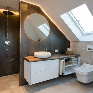 Kleines Modernes Badezimmer mit flächenbündigen Schrankfronten, weißen Schränken, Duschnische, Wandtoilette, beigefarbenen Fliesen, braunen Fliesen, weißer Wandfarbe, Aufsatzwaschbecken, Waschtisch aus Holz, beigem Boden, Falttür-Duschabtrennung, Zementfliesen, Zementfliesen und brauner Waschtischplatte in Dresden