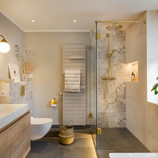 Modernes Badezimmer mit flächenbündigen Schrankfronten, hellbraunen Holzschränken, freistehender Badewanne, grauen Fliesen, grauer Wandfarbe, Aufsatzwaschbecken, Waschtisch aus Holz, grauem Boden und brauner Waschtischplatte in Dresden