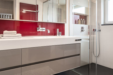 Großes Modernes Duschbad mit flächenbündigen Schrankfronten, grauen Schränken, bodengleicher Dusche, weißen Fliesen, roter Wandfarbe, integriertem Waschbecken, grauem Boden und weißer Waschtischplatte in Stuttgart