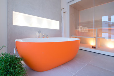 На фото: ванная комната в современном стиле с белыми фасадами, отдельно стоящей ванной, душем без бортиков, инсталляцией, серой плиткой, керамической плиткой, серыми стенами, накладной раковиной и столешницей из искусственного камня