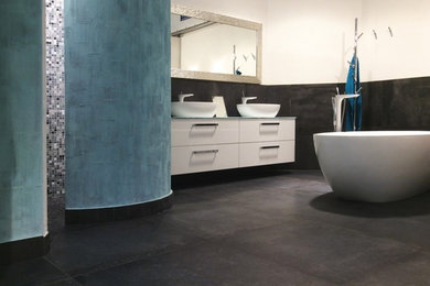 ミュンヘンにある巨大なコンテンポラリースタイルのおしゃれなマスターバスルーム (フラットパネル扉のキャビネット、白いキャビネット、置き型浴槽、オープン型シャワー、黒いタイル、石タイル、白い壁、セラミックタイルの床、ベッセル式洗面器) の写真