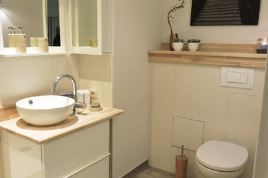 Kleines Maritimes Duschbad mit Aufsatzwaschbecken, Waschtisch aus Holz, Wandtoilette mit Spülkasten, beigen Fliesen, Keramikfliesen, weißer Wandfarbe und Keramikboden in Sonstige