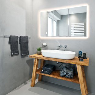 Modernes Badezimmer mit verzierten Schränken, hellbraunen Holzschränken, grauer Wandfarbe, Aufsatzwaschbecken, Waschtisch aus Holz und grauem Boden in Sonstige