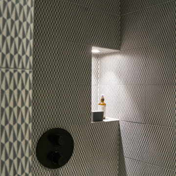 Geometrisch gemusterte Wandfliesen in der Dusche mit beleuchteter Nische