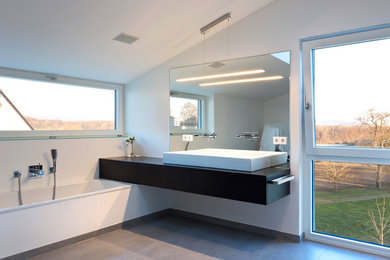 Imagen de cuarto de baño moderno grande con lavabo sobreencimera, armarios con paneles lisos, puertas de armario negras, bañera encastrada y paredes blancas