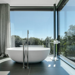 Modernes Badezimmer mit freistehender Badewanne und grauem Boden in München
