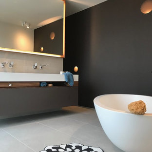 Mittelgroßes Modernes Badezimmer En Suite mit flächenbündigen Schrankfronten, dunklen Holzschränken, freistehender Badewanne, bodengleicher Dusche, Wandtoilette, grauen Fliesen, Keramikfliesen, Keramikboden, Aufsatzwaschbecken, Mineralwerkstoff-Waschtisch, grauem Boden, offener Dusche und schwarzer Wandfarbe in München