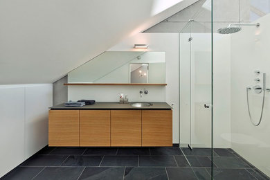 Idee per una stanza da bagno design di medie dimensioni con lavabo sottopiano, ante lisce, ante in legno chiaro, doccia ad angolo, pareti bianche e pavimento in ardesia