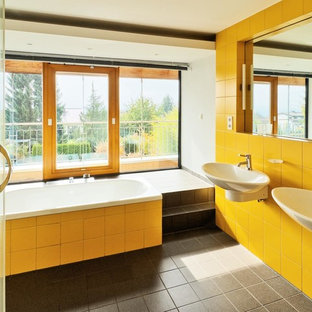 Immagine di una grande stanza da bagno minimal con lavabo sospeso, vasca da incasso, piastrelle gialle e pareti bianche