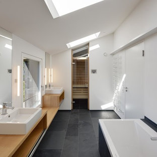 Inspiration för stora skandinaviska brunt en-suite badrum, med ett fristående handfat, träbänkskiva, ett platsbyggt badkar, vita väggar, skiffergolv, öppna hyllor, skåp i ljust trä och svart kakel