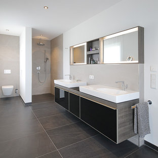 Großes Modernes Duschbad mit flächenbündigen Schrankfronten, schwarzen Schränken, offener Dusche, Wandtoilette mit Spülkasten, beigefarbenen Fliesen, Zementfliesen, weißer Wandfarbe, Zementfliesen, Aufsatzwaschbecken, Waschtisch aus Holz, schwarzem Boden, offener Dusche und grauer Waschtischplatte in München