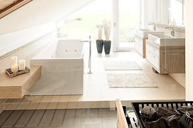 デュッセルドルフにある中くらいなコンテンポラリースタイルのおしゃれなマスターバスルーム (ベッセル式洗面器、フラットパネル扉のキャビネット、淡色木目調キャビネット、ベージュのタイル、白い壁、大型浴槽) の写真