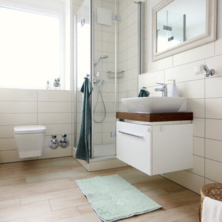 Mittelgroßes Modernes Duschbad mit flächenbündigen Schrankfronten, weißen Schränken, Eckdusche, Wandtoilette, weißen Fliesen, Porzellanfliesen, weißer Wandfarbe, Zementfliesen, Aufsatzwaschbecken, Waschtisch aus Holz, beigem Boden, Falttür-Duschabtrennung und brauner Waschtischplatte in Frankfurt am Main