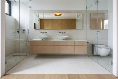 Cette photo montre une grande douche en alcôve tendance en bois brun avec un placard à porte plane, WC suspendus, un carrelage beige, des carreaux de céramique, un mur blanc, un sol en carrelage de céramique et une vasque.