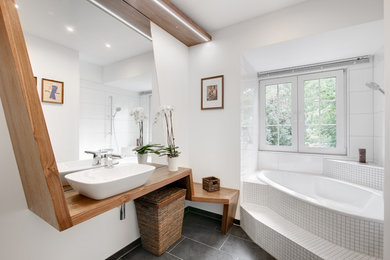 Inspiration pour une salle de bain design de taille moyenne avec une vasque, un plan de toilette en bois, une baignoire d'angle, un carrelage blanc, des carreaux de céramique, un mur blanc et un sol en ardoise.