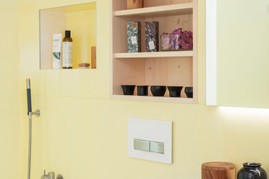 Kleines Modernes Badezimmer mit Einbaubadewanne, Wandtoilette mit Spülkasten, gelber Wandfarbe und Marmor-Waschbecken/Waschtisch in Sonstige