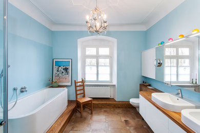 Design ideas for a medium sized farmhouse bathroom in Stuttgart with flat-panel cabinets, white cabinets, an alcove bath, a corner shower, a wall mounted toilet, brown tiles, blue walls, terracotta flooring, a built-in sink, wooden worktops, brown floors, a hinged door and brown worktops.