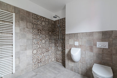 Ispirazione per una piccola stanza da bagno minimal con doccia a filo pavimento, WC sospeso, piastrelle grigie, pareti beige e pavimento in cementine