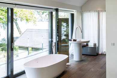 Foto di una grande stanza da bagno padronale contemporanea con vasca freestanding, parquet scuro e top in superficie solida