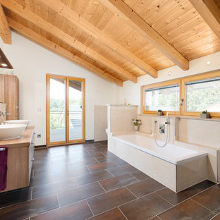 Großes Skandinavisches Badezimmer En Suite mit flächenbündigen Schrankfronten, Einbaubadewanne, beigefarbenen Fliesen, Keramikfliesen, weißer Wandfarbe, Aufsatzwaschbecken, Waschtisch aus Holz, hellbraunen Holzschränken, braunem Boden und beiger Waschtischplatte in Nürnberg