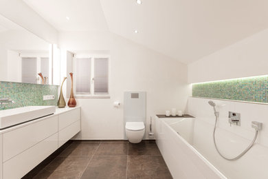 Photo of a medium sized rustic shower room bathroom in Munich with flat-panel cabinets, white cabinets, a built-in bath, a two-piece toilet, multi-coloured tiles, mosaic tiles, white walls, a vessel sink, brown floors and white worktops.