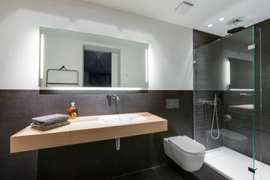 Inspiration for a small modern 3/4 black tile and matchstick tile black floor, single-sink and tray ceiling bathroom remodel in Cologne with a wall-mount toilet, wood countertops, beige countertops, beaded inset cabinets, light wood cabinets, white walls, an integrated sink, a niche and a floating vanity