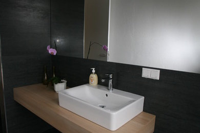 Modernes Badezimmer mit schwarzen Fliesen, schwarzer Wandfarbe, Aufsatzwaschbecken und Waschtisch aus Holz in Nürnberg