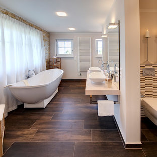Großes Mediterranes Badezimmer En Suite mit offenen Schränken, braunen Schränken, freistehender Badewanne, offener Dusche, Toilette mit Aufsatzspülkasten, braunen Fliesen, Porzellanfliesen, brauner Wandfarbe, Porzellan-Bodenfliesen, Aufsatzwaschbecken, Waschtisch aus Holz, braunem Boden, offener Dusche und beiger Waschtischplatte in München