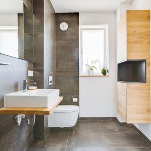 Modernes Badezimmer mit grauen Fliesen, weißer Wandfarbe, Aufsatzwaschbecken, Waschtisch aus Holz, grauem Boden, brauner Waschtischplatte und Einzelwaschbecken in Nürnberg