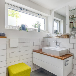 Kleines Modernes Badezimmer mit flächenbündigen Schrankfronten, weißen Schränken, weißen Fliesen, weißer Wandfarbe, Aufsatzwaschbecken, Waschtisch aus Holz, grauem Boden, brauner Waschtischplatte, Einzelwaschbecken und schwebendem Waschtisch in München