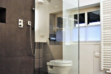 Mittelgroßes Modernes Duschbad mit offener Dusche, Wandtoilette, braunen Fliesen, weißer Wandfarbe, braunem Boden und offener Dusche in München