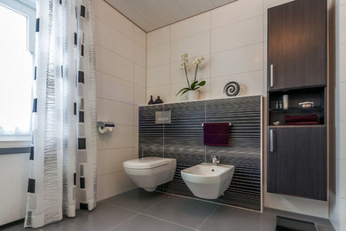 Mittelgroßes Modernes Badezimmer mit flächenbündigen Schrankfronten, dunklen Holzschränken, Wandtoilette, schwarz-weißen Fliesen, Porzellanfliesen und grauem Boden in München