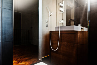 Großes Modernes Badezimmer mit flächenbündigen Schrankfronten, beigen Schränken, Einbaubadewanne, bodengleicher Dusche, Wandtoilette, beigen Fliesen, Kalkfliesen, weißer Wandfarbe, braunem Holzboden, Waschtischkonsole, Mineralwerkstoff-Waschtisch, braunem Boden und Falttür-Duschabtrennung in München