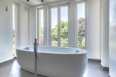 Imagen de cuarto de baño actual grande con bañera exenta, paredes blancas y ventanas
