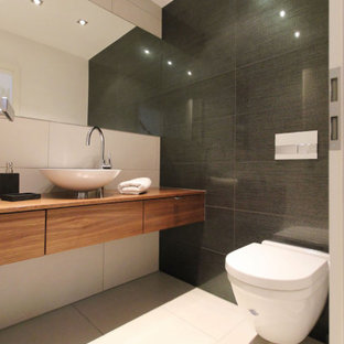 Großes Modernes Duschbad mit flächenbündigen Schrankfronten, hellbraunen Holzschränken, Wandtoilette, grauen Fliesen, Aufsatzwaschbecken, Waschtisch aus Holz, beigem Boden, brauner Waschtischplatte, Einzelwaschbecken und schwebendem Waschtisch in Dortmund