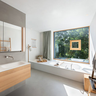 Geräumiges Modernes Badezimmer En Suite mit Einbaubadewanne, Betonboden, grauem Boden, weißer Waschtischplatte, hellen Holzschränken, grauen Fliesen, Porzellanfliesen, weißer Wandfarbe, integriertem Waschbecken, Doppelwaschbecken, schwebendem Waschtisch und flächenbündigen Schrankfronten in München