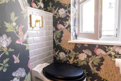 Immagine di un bagno di servizio tradizionale di medie dimensioni con WC sospeso, piastrelle grigie, piastrelle in ceramica, pavimento con piastrelle in ceramica, lavabo a consolle e carta da parati